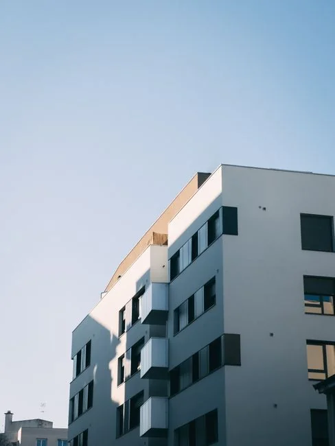 Une femme en pull gris essuie une table avec soin, illustrant le ménage à domicile dans le confort.